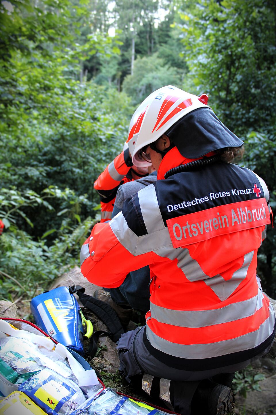 Übung im Gelände: Frau hockt mit Material auf dem Boden